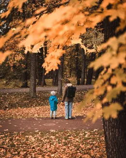A man and a child walking through a park by E I courtesy of Unsplash.