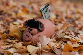 a piggy bank with a dollar bill sticking out of it by Alla Kemelmakher courtesy of Unsplash.