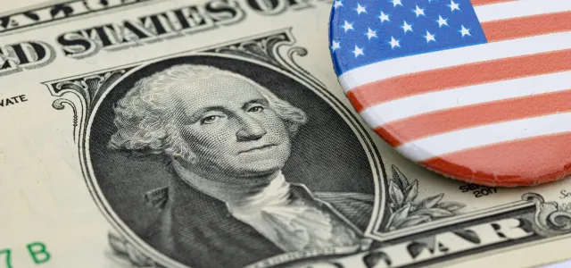 a one dollar bill and a button with the american flag on it by Marek Studzinski courtesy of Unsplash.
